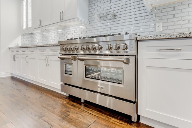 kitchen featuring light stone countertops, double oven range, white cabinetry, and tasteful backsplash