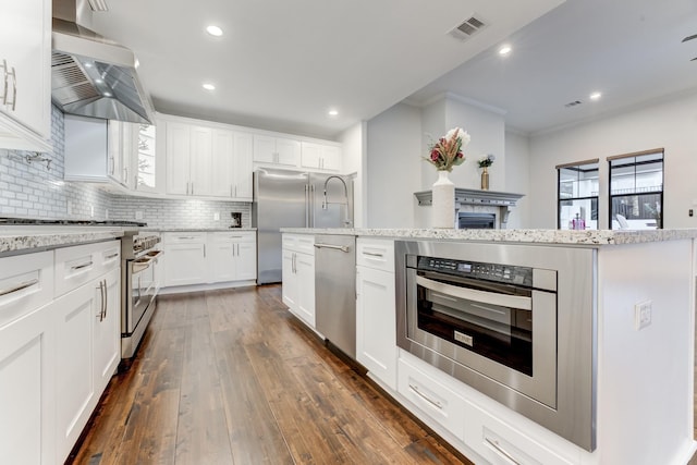 kitchen featuring dark hardwood / wood-style floors, backsplash, wall chimney range hood, high quality appliances, and white cabinets