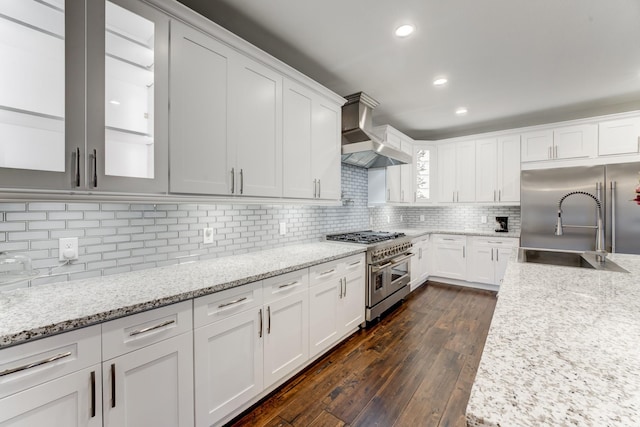 kitchen featuring light stone countertops, wall chimney exhaust hood, high end appliances, and white cabinetry