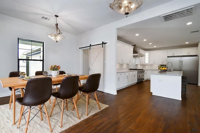 dining space featuring a barn door and dark hardwood / wood-style floors