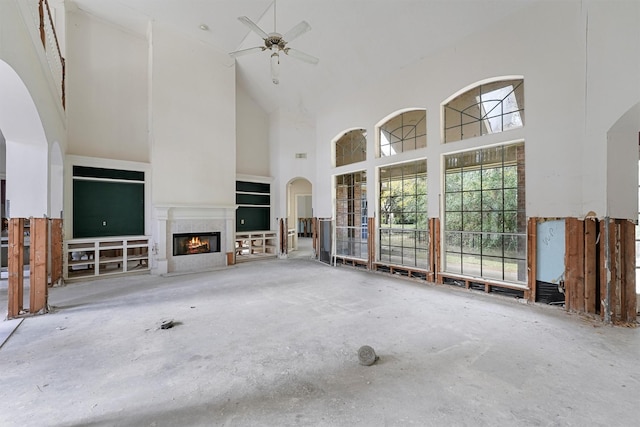 unfurnished living room with ceiling fan and a high ceiling