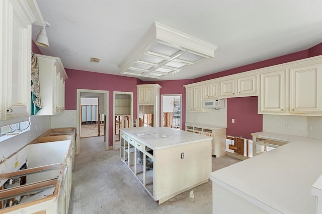 kitchen featuring cream cabinetry, a center island, and backsplash