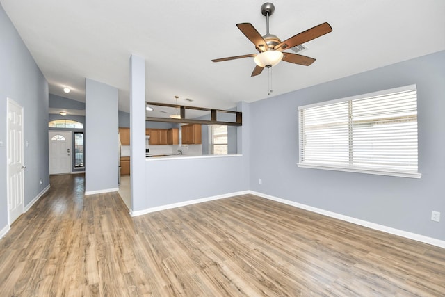 unfurnished living room with ceiling fan, wood-type flooring, and vaulted ceiling