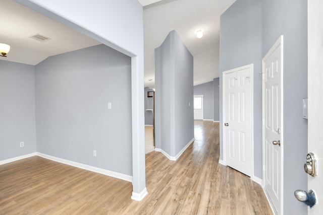 hall featuring light wood-type flooring and lofted ceiling