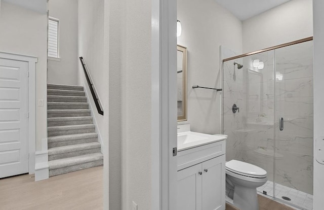 bathroom with hardwood / wood-style floors, vanity, toilet, and walk in shower