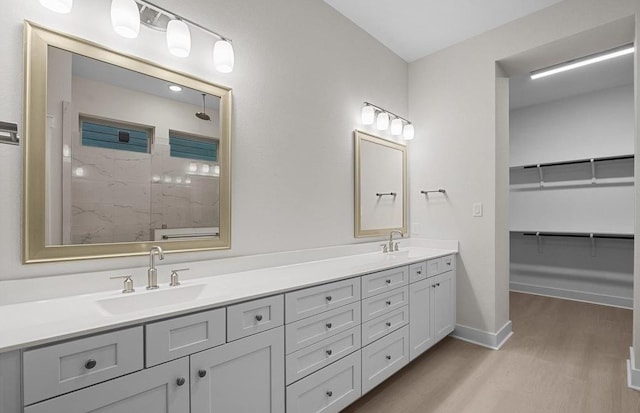 bathroom with hardwood / wood-style floors, vanity, and a tile shower