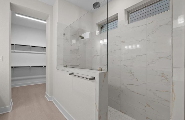 bathroom with tiled shower and hardwood / wood-style floors