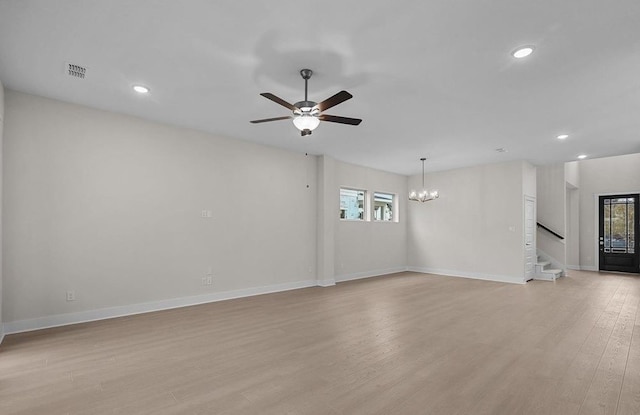 unfurnished living room with ceiling fan with notable chandelier and light wood-type flooring