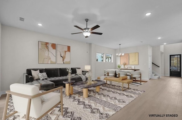 living room featuring light hardwood / wood-style flooring and ceiling fan with notable chandelier