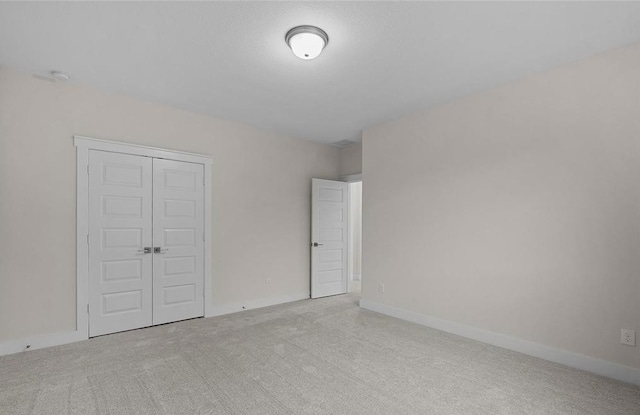 unfurnished bedroom featuring light carpet and a closet