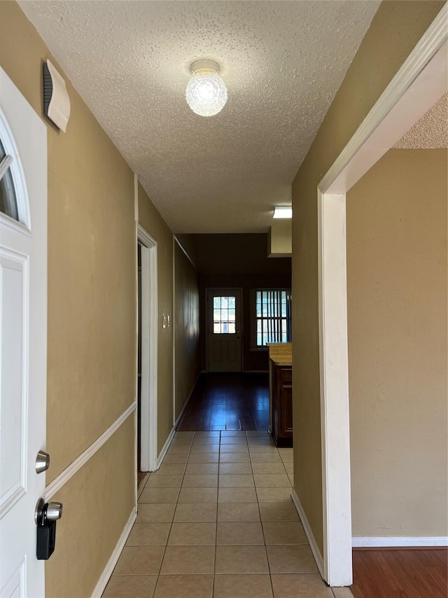 hall featuring tile patterned flooring and a textured ceiling