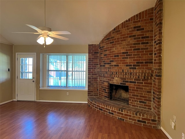 unfurnished living room with a brick fireplace, dark hardwood / wood-style flooring, vaulted ceiling, and ceiling fan