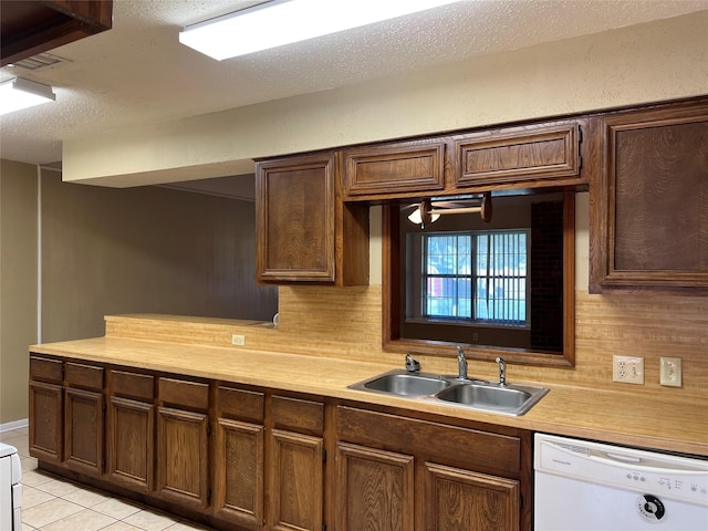 kitchen with white dishwasher, sink, a textured ceiling, tasteful backsplash, and light tile patterned flooring