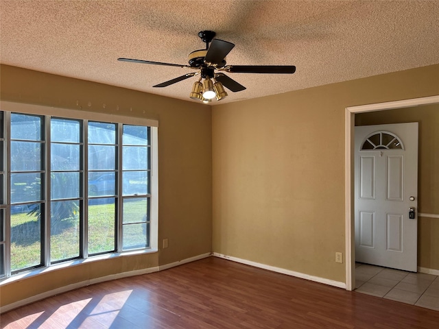 spare room with wood-type flooring, a textured ceiling, a wealth of natural light, and ceiling fan