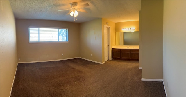 unfurnished room with ceiling fan, dark carpet, sink, and a textured ceiling