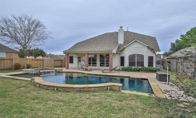 rear view of property featuring a pool with hot tub, a yard, and a patio