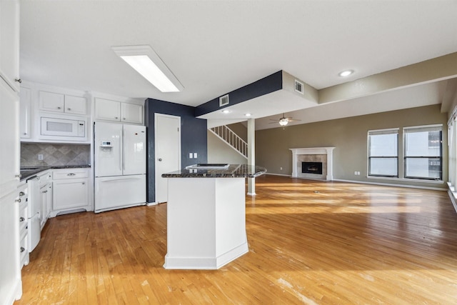 kitchen with white cabinetry, light wood-type flooring, white appliances, and dark stone counters