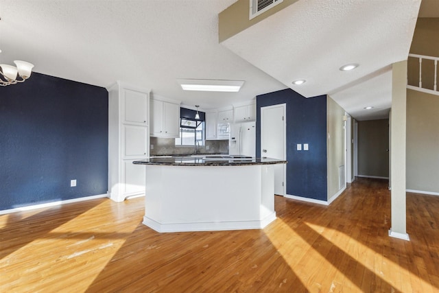 kitchen with white cabinetry, a center island, white appliances, and light hardwood / wood-style flooring