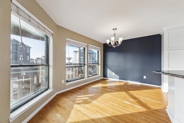 unfurnished dining area with an inviting chandelier and hardwood / wood-style flooring