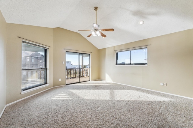 carpeted empty room with ceiling fan, lofted ceiling, plenty of natural light, and a textured ceiling