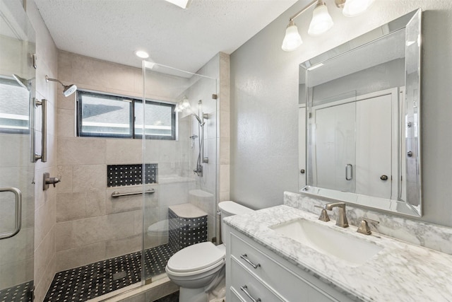 bathroom featuring a shower with door, vanity, a textured ceiling, and toilet