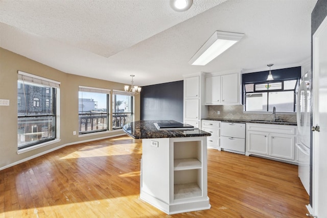 kitchen featuring pendant lighting, a breakfast bar area, dishwasher, white cabinetry, and a center island