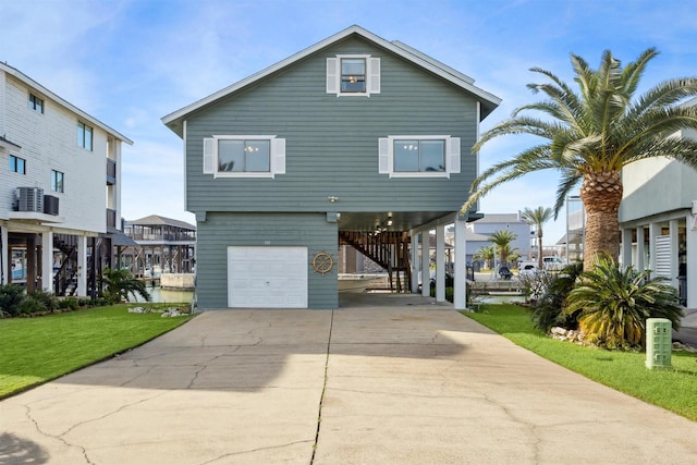 view of front facade featuring central air condition unit, a front lawn, a garage, and a carport