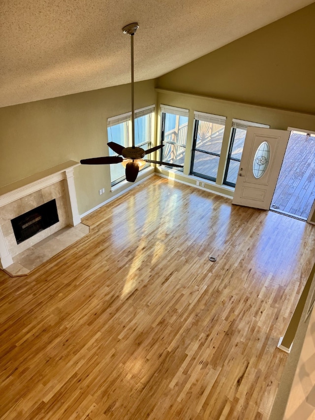 unfurnished living room with a premium fireplace, lofted ceiling, a textured ceiling, and light hardwood / wood-style floors