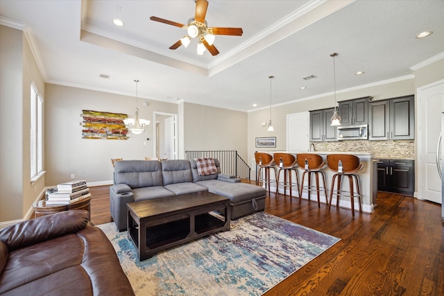 living room featuring a tray ceiling, crown molding, ceiling fan with notable chandelier, and dark hardwood / wood-style floors