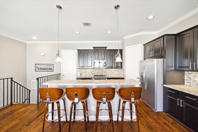 kitchen featuring a center island with sink, hanging light fixtures, and appliances with stainless steel finishes