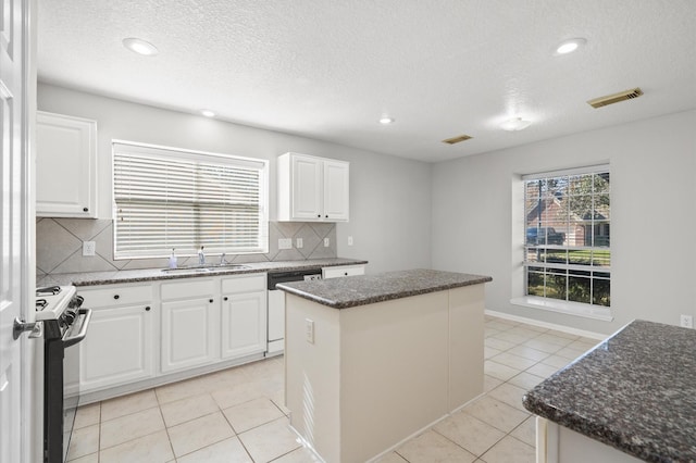 kitchen with sink, white cabinetry, decorative backsplash, a kitchen island, and electric stove