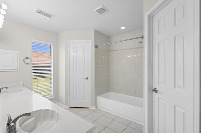 bathroom featuring vanity, tile patterned flooring, a textured ceiling, and tiled shower / bath combo