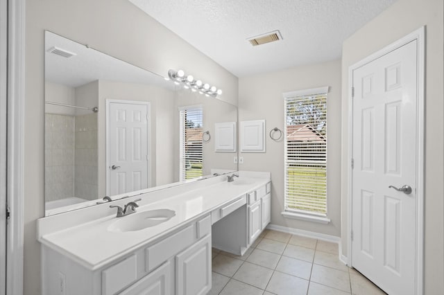 bathroom featuring vanity, tile patterned flooring, tiled shower / bath combo, and a textured ceiling