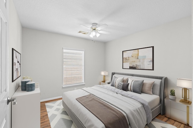 bedroom featuring a textured ceiling, ceiling fan, and light wood-type flooring