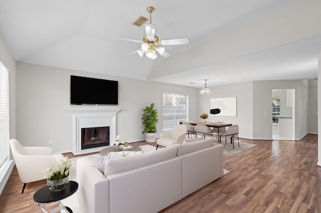 living room featuring ceiling fan with notable chandelier, hardwood / wood-style flooring, and vaulted ceiling