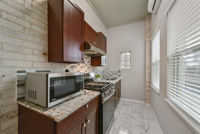 kitchen featuring decorative backsplash, light stone countertops, a wall mounted AC, sink, and stainless steel gas stove