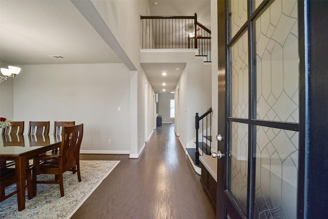 foyer entrance with dark wood-type flooring, a high ceiling, and a notable chandelier