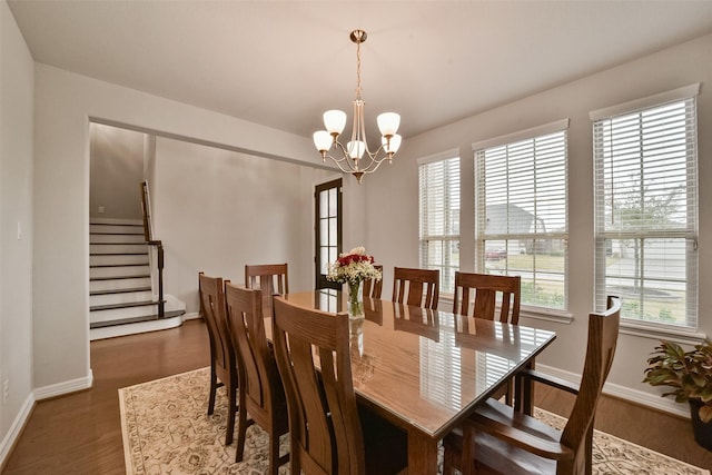 dining room with dark hardwood / wood-style floors and an inviting chandelier