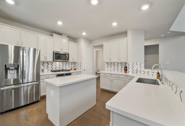 kitchen with kitchen peninsula, stainless steel appliances, white cabinetry, and sink