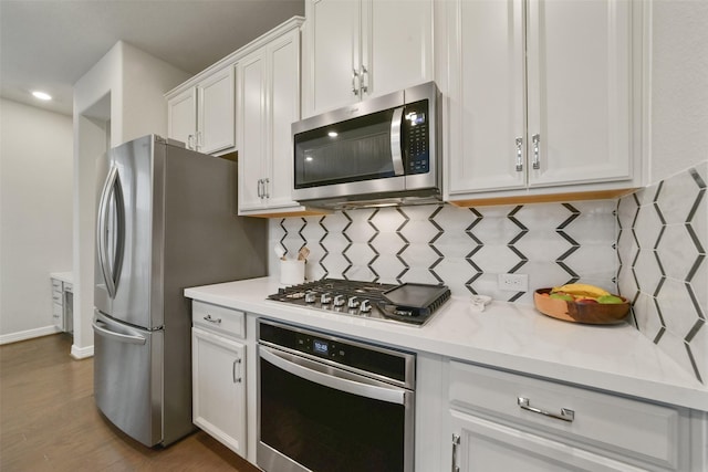 kitchen featuring white cabinets, decorative backsplash, light stone countertops, dark hardwood / wood-style flooring, and stainless steel appliances