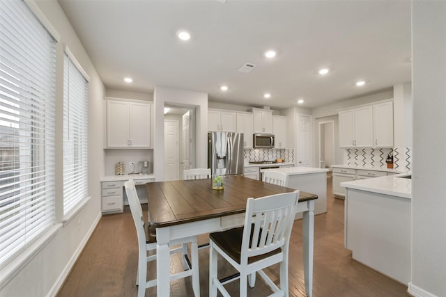 kitchen with decorative backsplash, white cabinetry, dark wood-type flooring, and stainless steel appliances