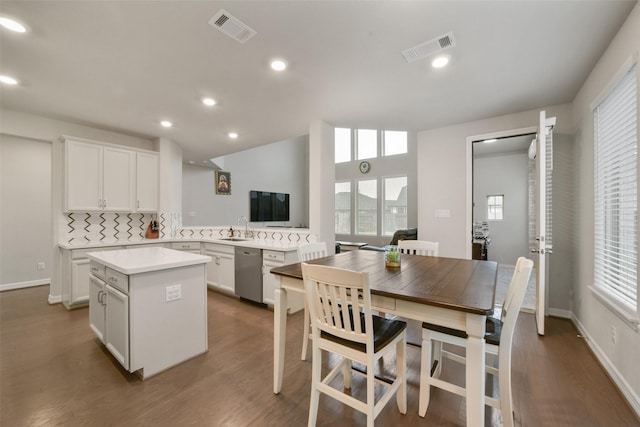 kitchen with dishwasher, backsplash, white cabinetry, and a kitchen island