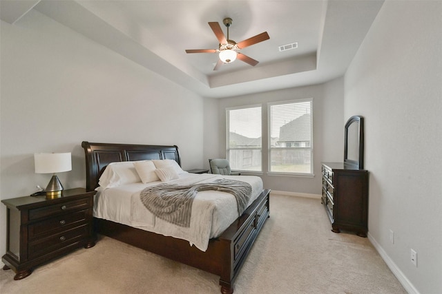 carpeted bedroom featuring a raised ceiling and ceiling fan