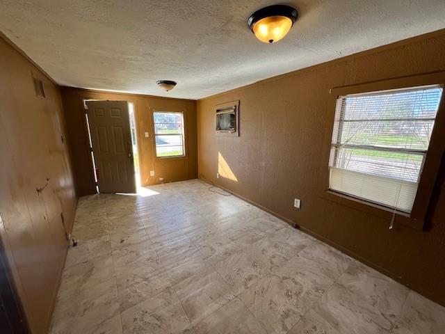 spare room with a textured ceiling and wood walls