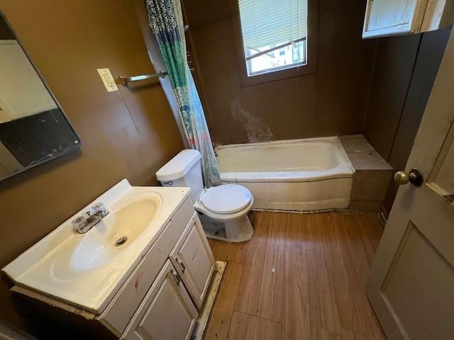 full bathroom featuring vanity, wood-type flooring, toilet, and shower / bathtub combination with curtain