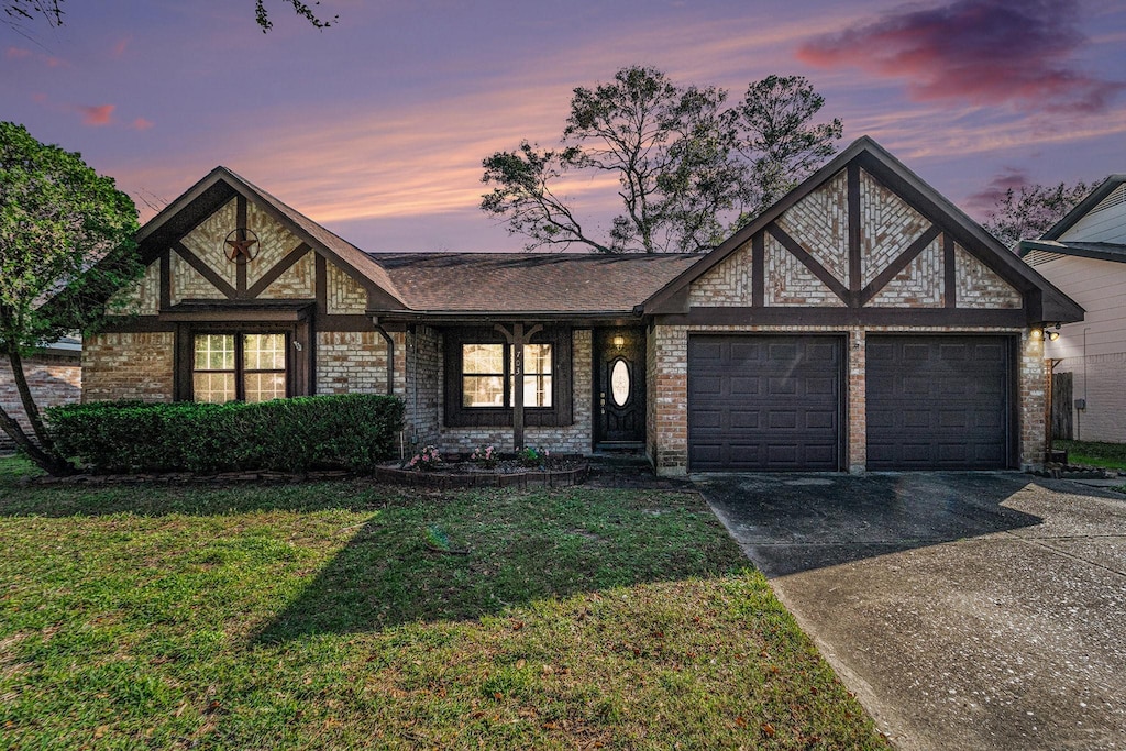 tudor-style house featuring a lawn and a garage