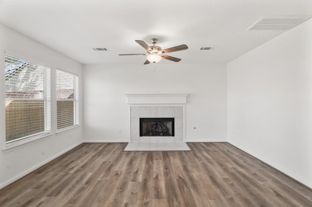 unfurnished living room featuring ceiling fan, a fireplace, and dark wood-type flooring