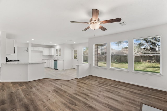 unfurnished living room featuring ceiling fan, light wood-type flooring, and sink