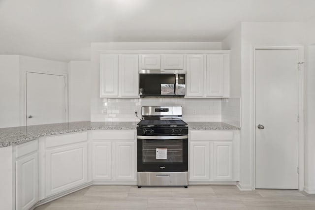 kitchen featuring white cabinets, stainless steel appliances, and tasteful backsplash