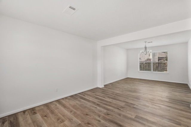 unfurnished room with wood-type flooring and an inviting chandelier